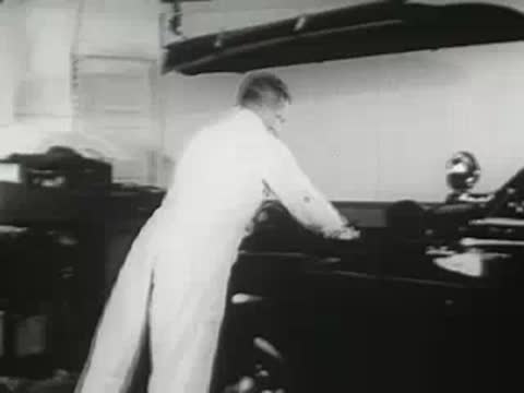 Mechanic working on car in garage, 1940s.