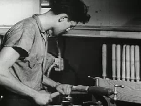 Woodworker operating lathe in workshop, 1940s.