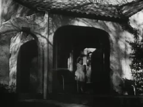 People emerging from arched entrance of building, 1940s.