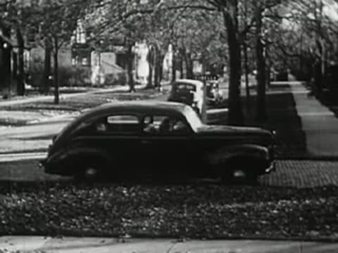 Parked car along residential street with bare trees, 1940s.