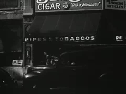 Storefront at night with cigar and tobacco sign, 1940s.