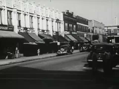 Busy downtown street intersection with traffic, 1940s.