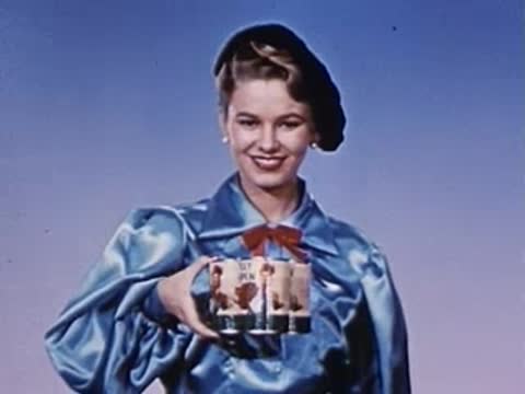 woman in blue satin top holding decorative cans in her hands