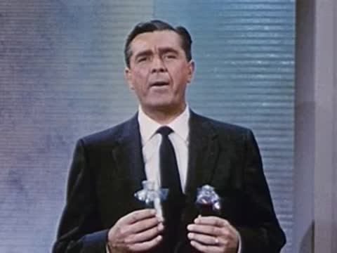 man in suit standing behind table holding small glass bottles