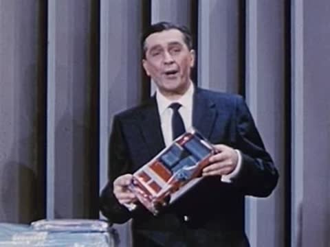 man in dark suit holding a product box and examining it