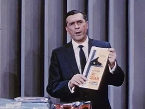 man holding up a booklet or instruction sheet for the audience