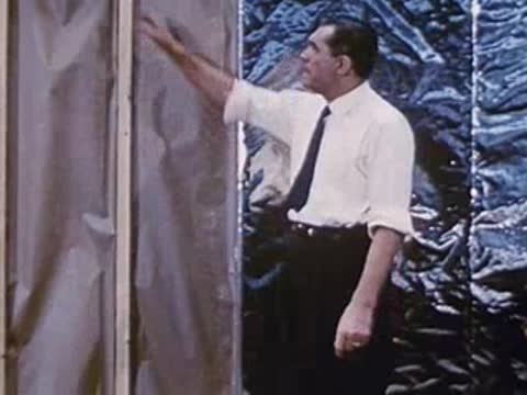 man in white shirt talking and gesturing in front of shiny background