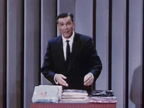 Man in suit stands behind desk with shirt packages in studio