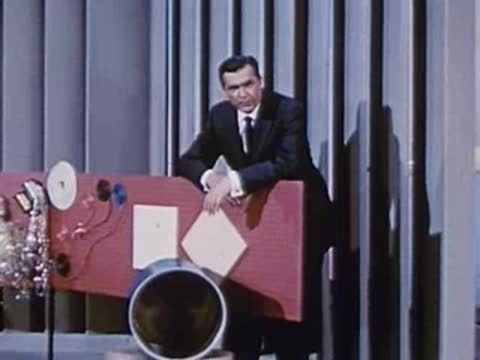 Man in suit leans on display board next to various test apparatus