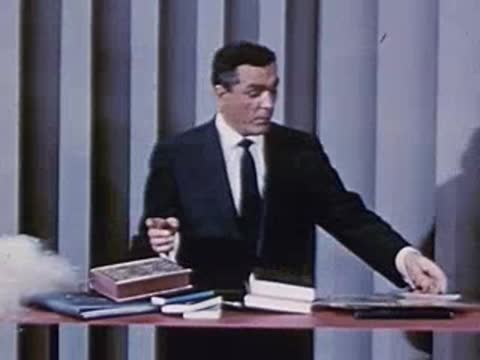 Man in suit demonstrates fluffy material and shows red circular objects