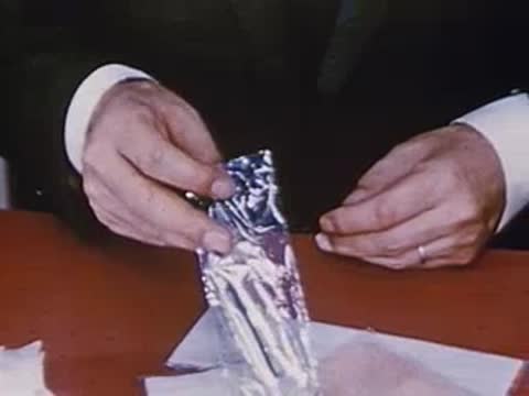 Close-up of hands opening a clear plastic packet containing an item