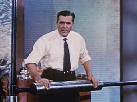man behind table demonstrating with a long metallic roller