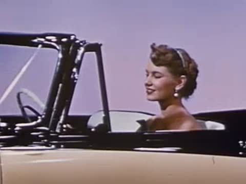 Woman sits inside a convertible car, looking forward