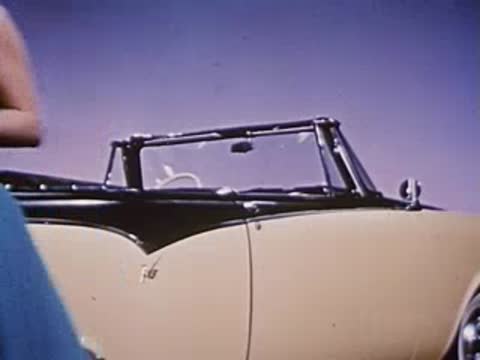 Woman in blue dress walks away from convertible car