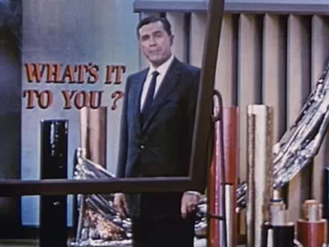 Man in suit stands next to display with sign in studio