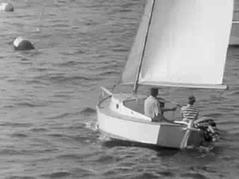 A small sailboat moving across the ocean waves near the coast.