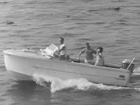 A motorboat speeding across the water with passengers waving from the deck.