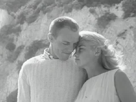 A couple embraces on the beach near a child with a ball.