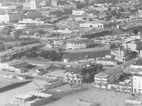 An aerial view shows a coastal town and sandy beach.