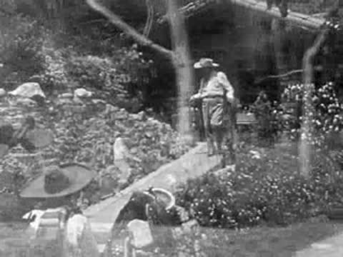 A cowboy in a sombrero walks along a stone path in 1950s California.