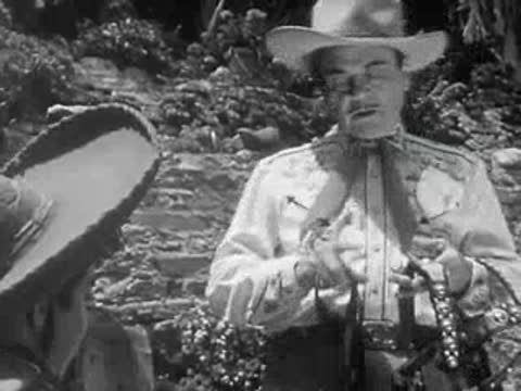 A cowboy in a western shirt holds a saddle in 1950s California.