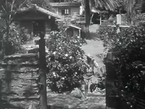 A cowboy walks through a stone-paved garden gate in 1950s California.