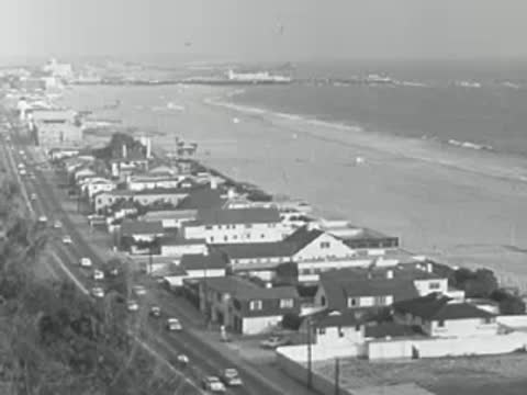 Aerial view of a coastal highway and beach houses in 1950s California.
