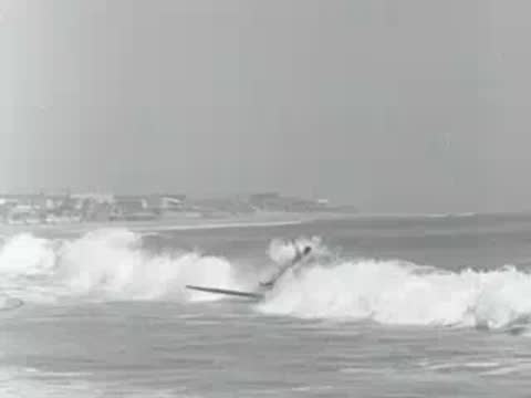 A surfer rides a wave on the ocean in 1950s California.