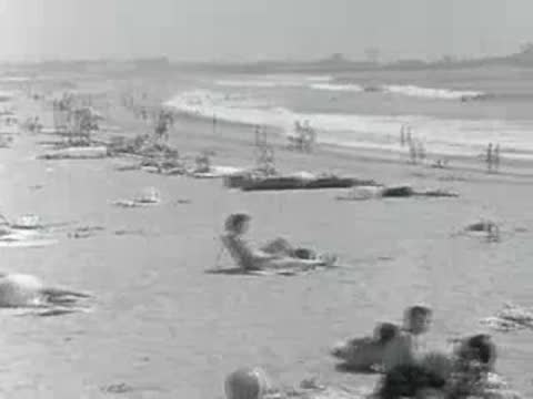 People relax on a crowded beach with umbrellas in 1950s California.