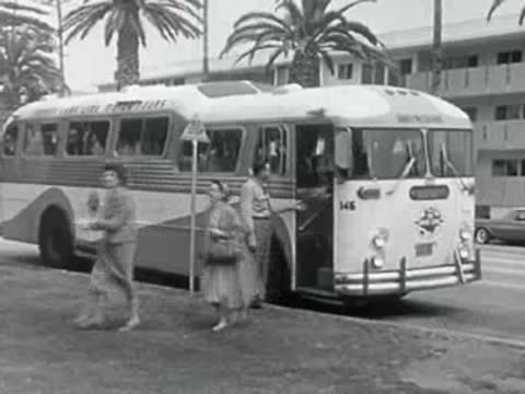 A classic passenger bus at a bus stop in 1950s California.