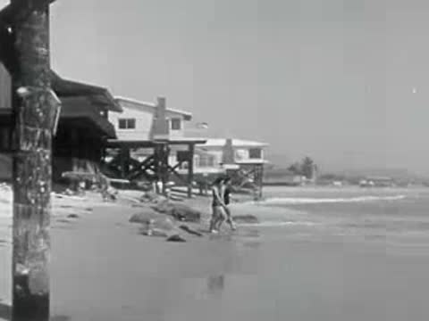 Two children run out of the ocean waves onto a sandy beach.