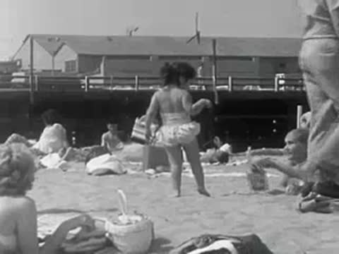 A young child in a swimsuit walks across the sandy beach.