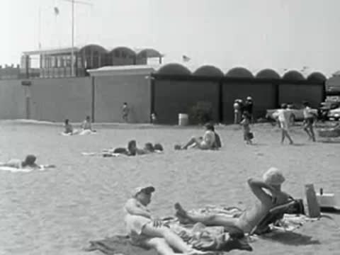 Lifeguard station and people relaxing on the sand at the beach.