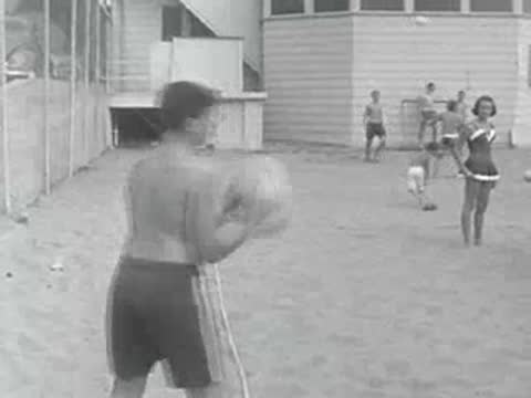 A young man plays volleyball on an outdoor sand court.