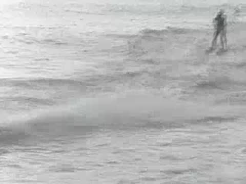 A person water-skiing behind a fast motorboat in open coastal waters.