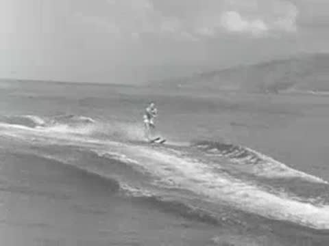 A motorboat pulling a water skier across the open ocean water.