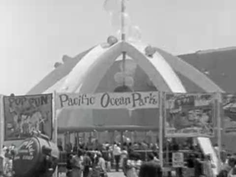 The entrance archway to Pacific Ocean Park with visitors walking around.