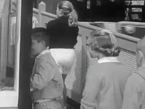 Children and teenagers walk near a roller coaster ride in the park.