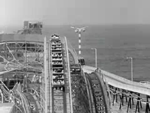 POV shot descending a roller coaster drop toward the ocean view.