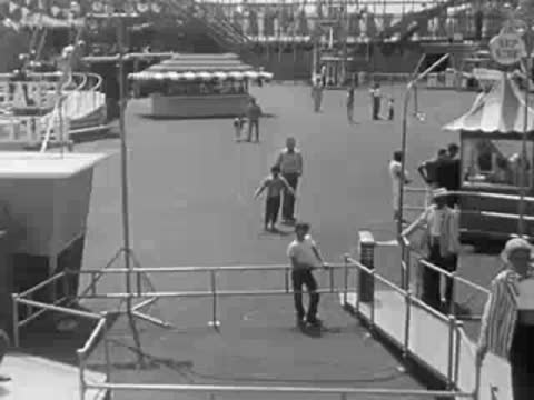 High-angle view of a roller coaster track structure with amusement park crowds.