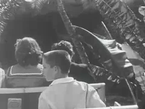 Children riding a boat-style amusement park attraction looking ahead.