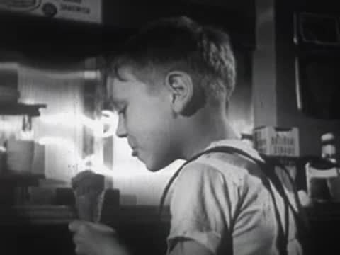 Young boy eating an ice cream cone indoors.