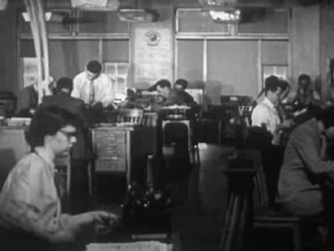 People working at desks in an office environment with typewriters.