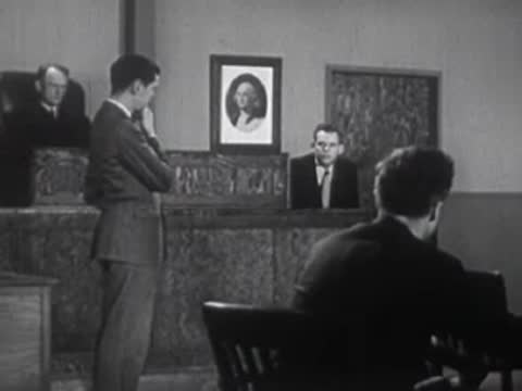 Men gathered around an office desk discussing documents.