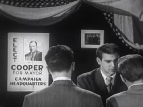 Men in a campaign headquarters setting with political posters.