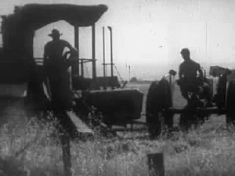 Farmer driving a tractor harvesting crops in a field.