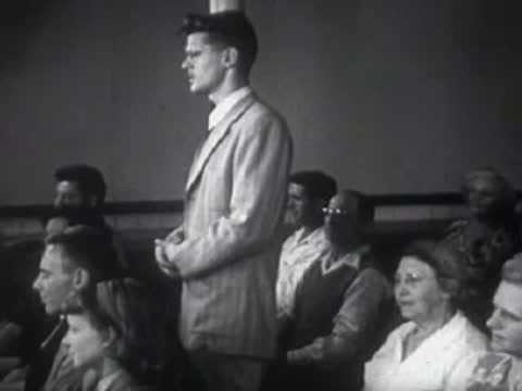Man standing and speaking at a podium before an audience.