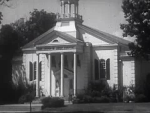 White colonial-style church building with columns and trees in front.