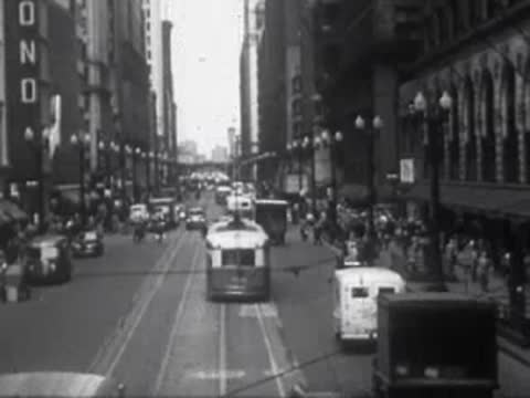Busy city street scene with cars, buses, and pedestrians in traffic.