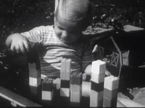 Indigenous woman and child looking forward, followed by a toddler playing with blocks.